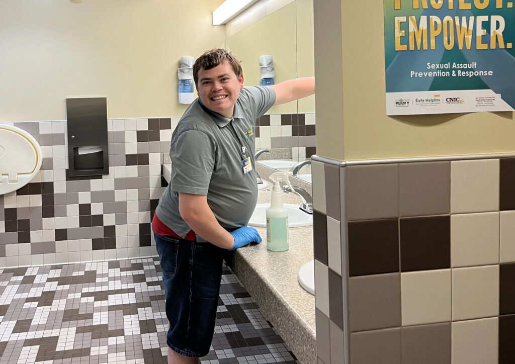 Golden Rule Industries employee cleaning restroom sink with disinfectant, janitorial services in action