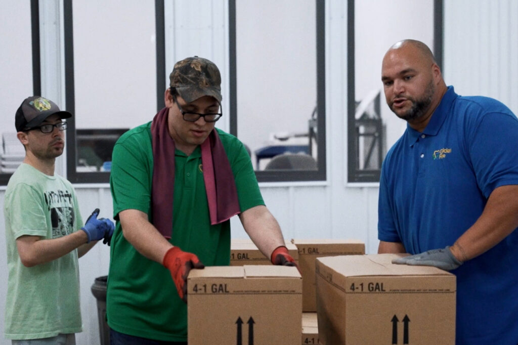 Team members packaging and handling boxes in a warehouse at Golden Rule Industries